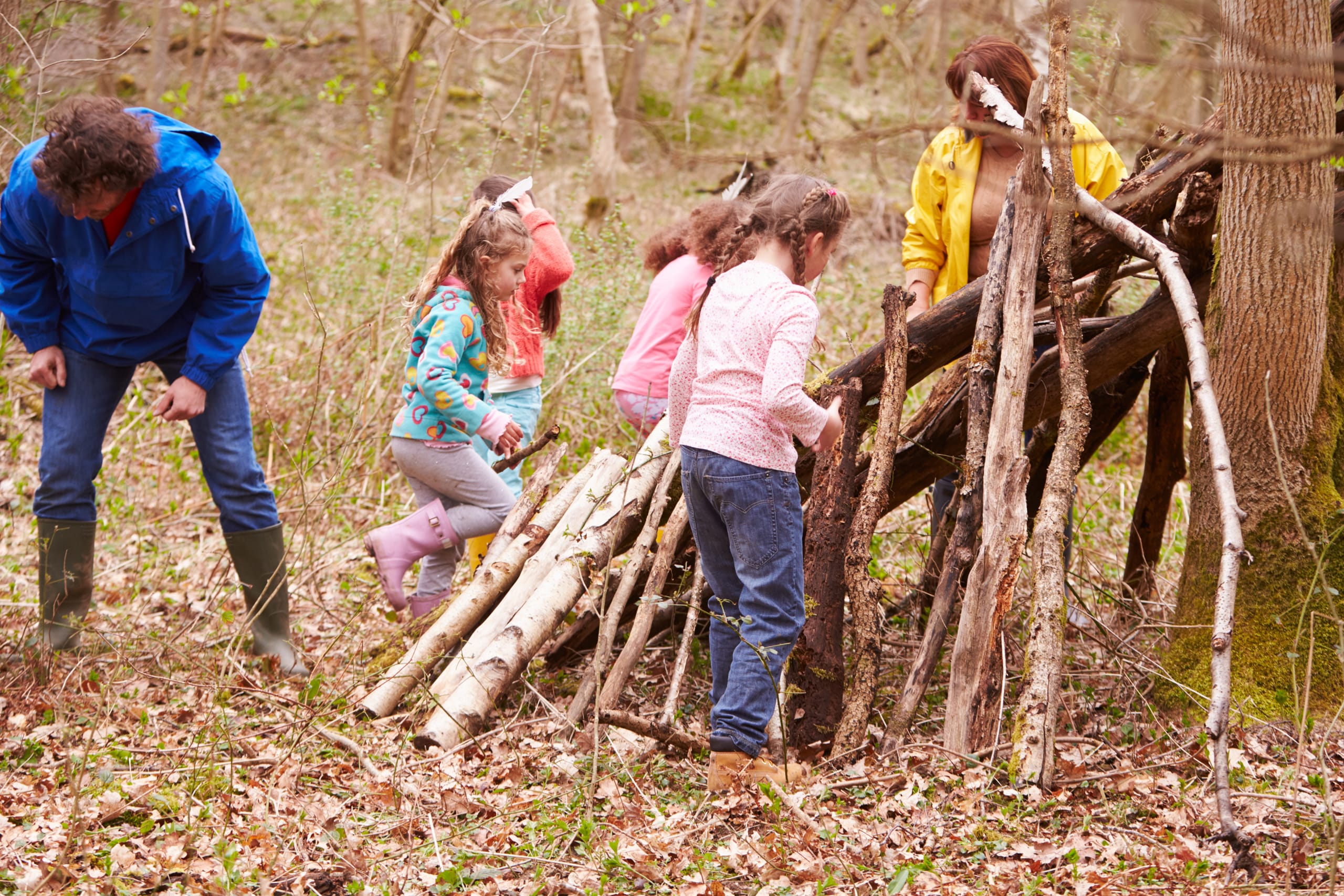 A family building a den from tree branches in the woods