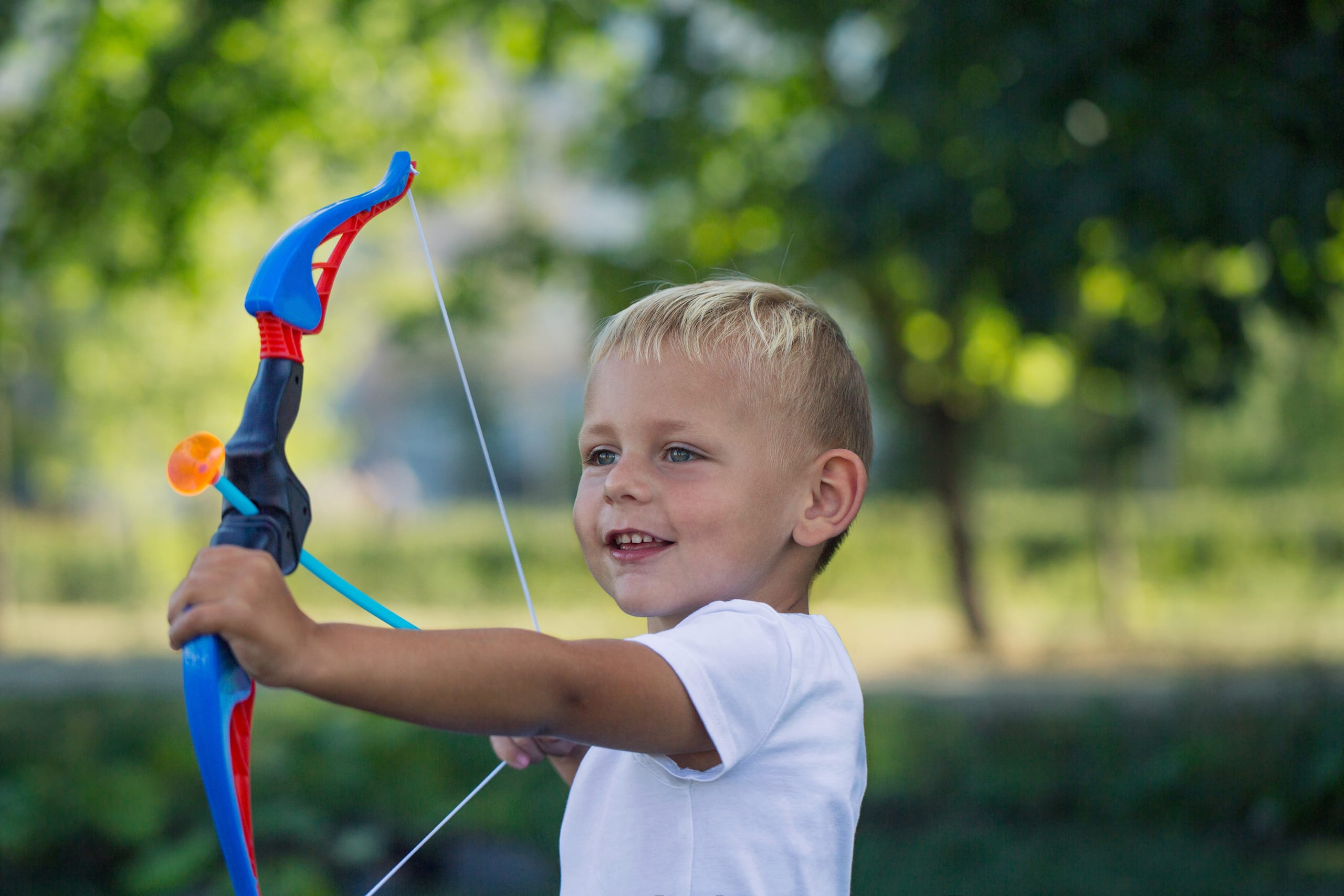 A little boy shoots out a toy bow