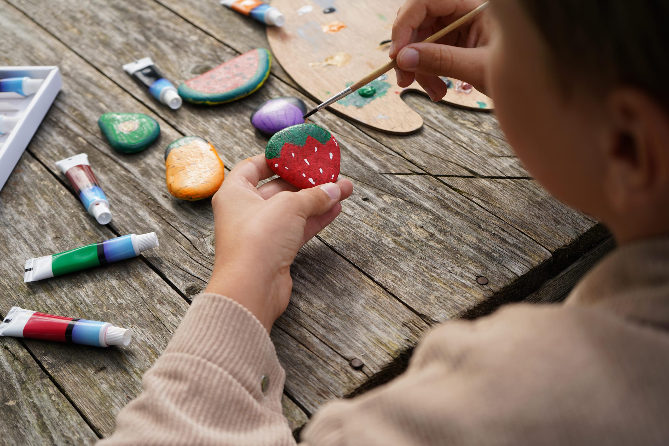 a child painting a pebble to look like a strawberry